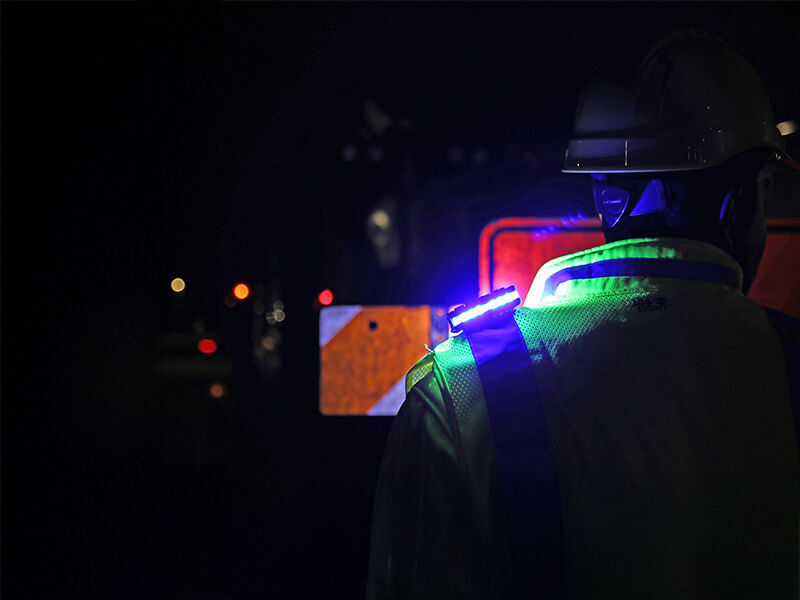 person in a vest and hardhat wearing a guardian angel device in front of construction signs