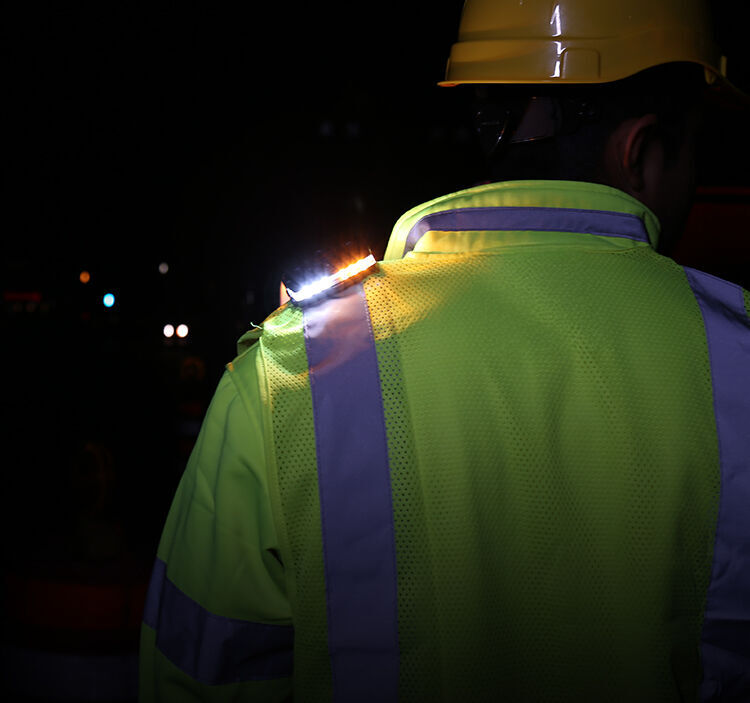 person in hard hat with guardian angel device mounted on the shoulder of a reflective vest